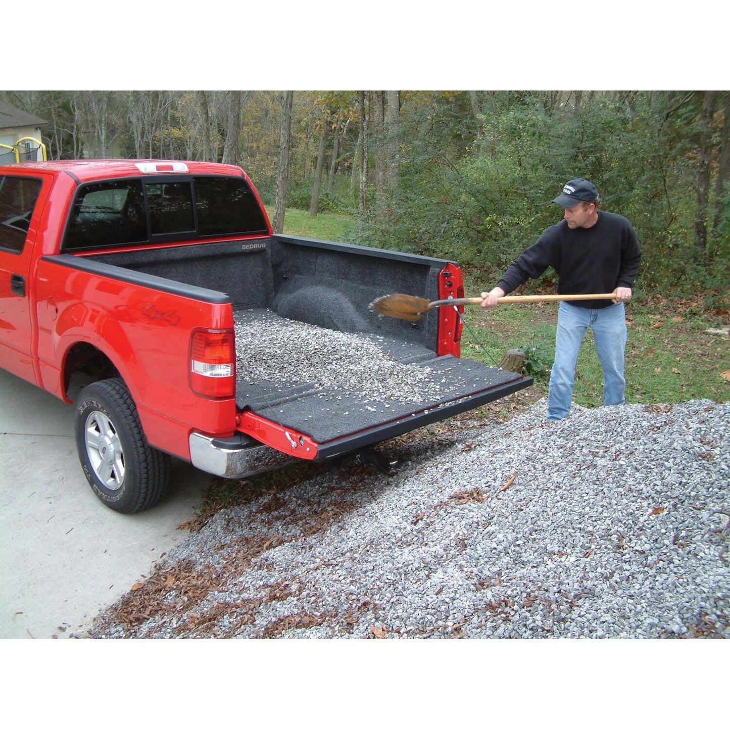 Person using a shovel to load gravel into a truck bed with BedRug 23-25 Colorado/Canyon Crew Cab 5' Bed Liner w/ Tailgate Mat - Charcoal (BRB23CCK).