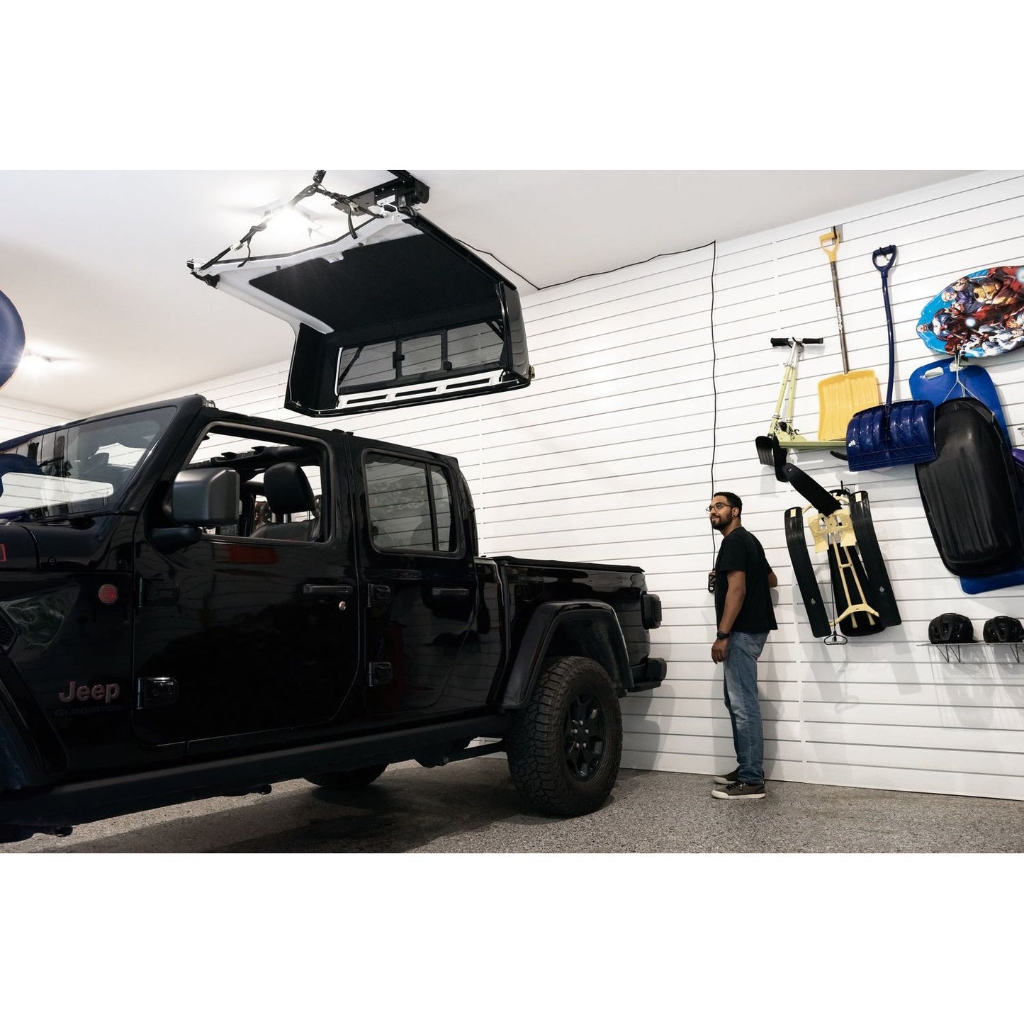 BESTOP | HOSS Hardtop Hoist Jeep 2018-26 Wrangler JL Black Bestop | 42820-01 in a garage with a man standing nearby.