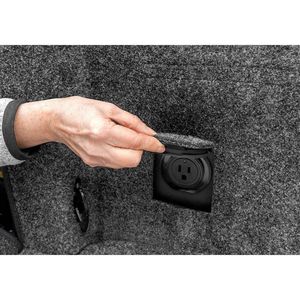 Hand removing cover from power outlet in BedRug 2015-2025 Ford F-150 6'7" Bed Liner w/ Tailgate Mat - Charcoal (BRQ15SBK)