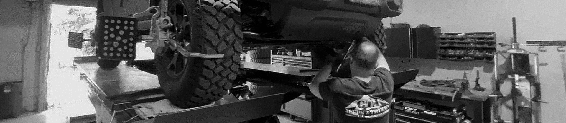 Jeep on a lift in a mechanics shop being worked on 