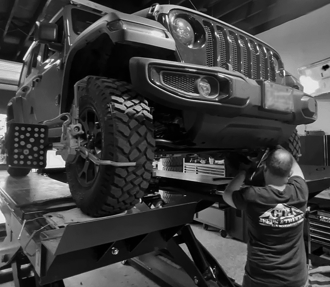 jeep on a lift in a mechanic shop being worked on