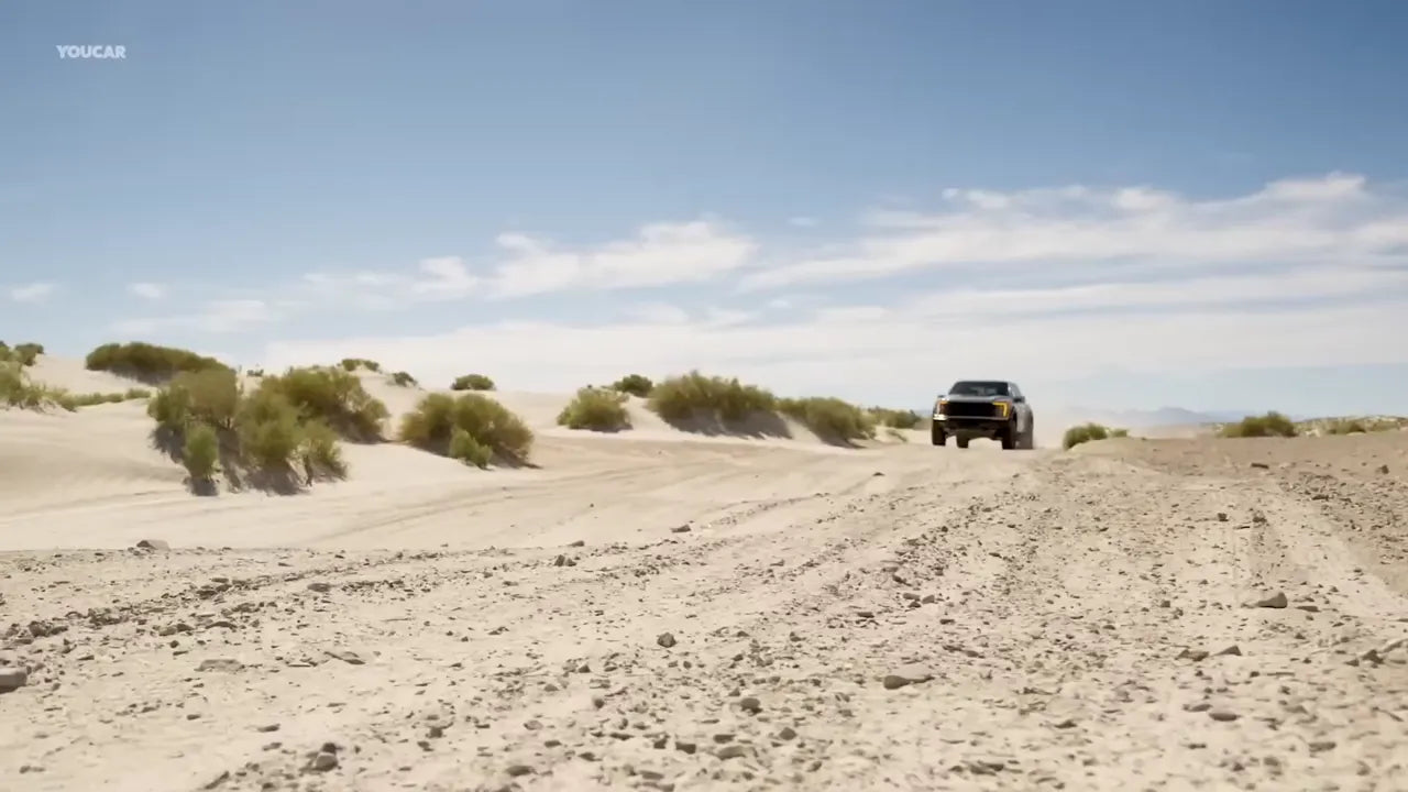 Trucks driving off road through a desert on a sunny day